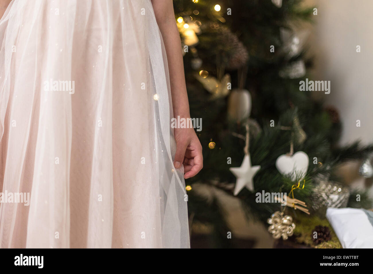 Taille abwärts Schuss von einem Mädchen in rosa stand vor Weihnachtsbaum Stockfoto