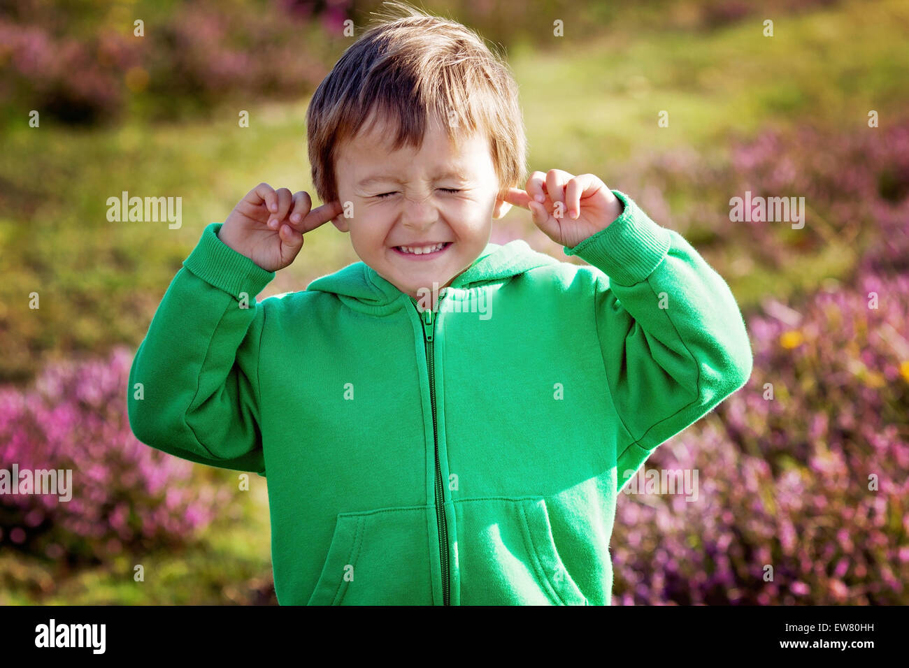 Kleiner Junge hält seine Hände über die Ohren nicht zu hören, so dass süße lustige Gesicht Stockfoto