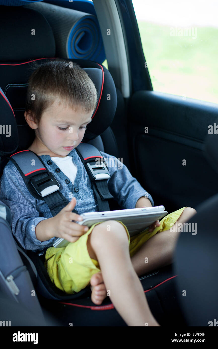 Netter Junge, spielen auf Tablet im Auto, während der Reise Stockfoto