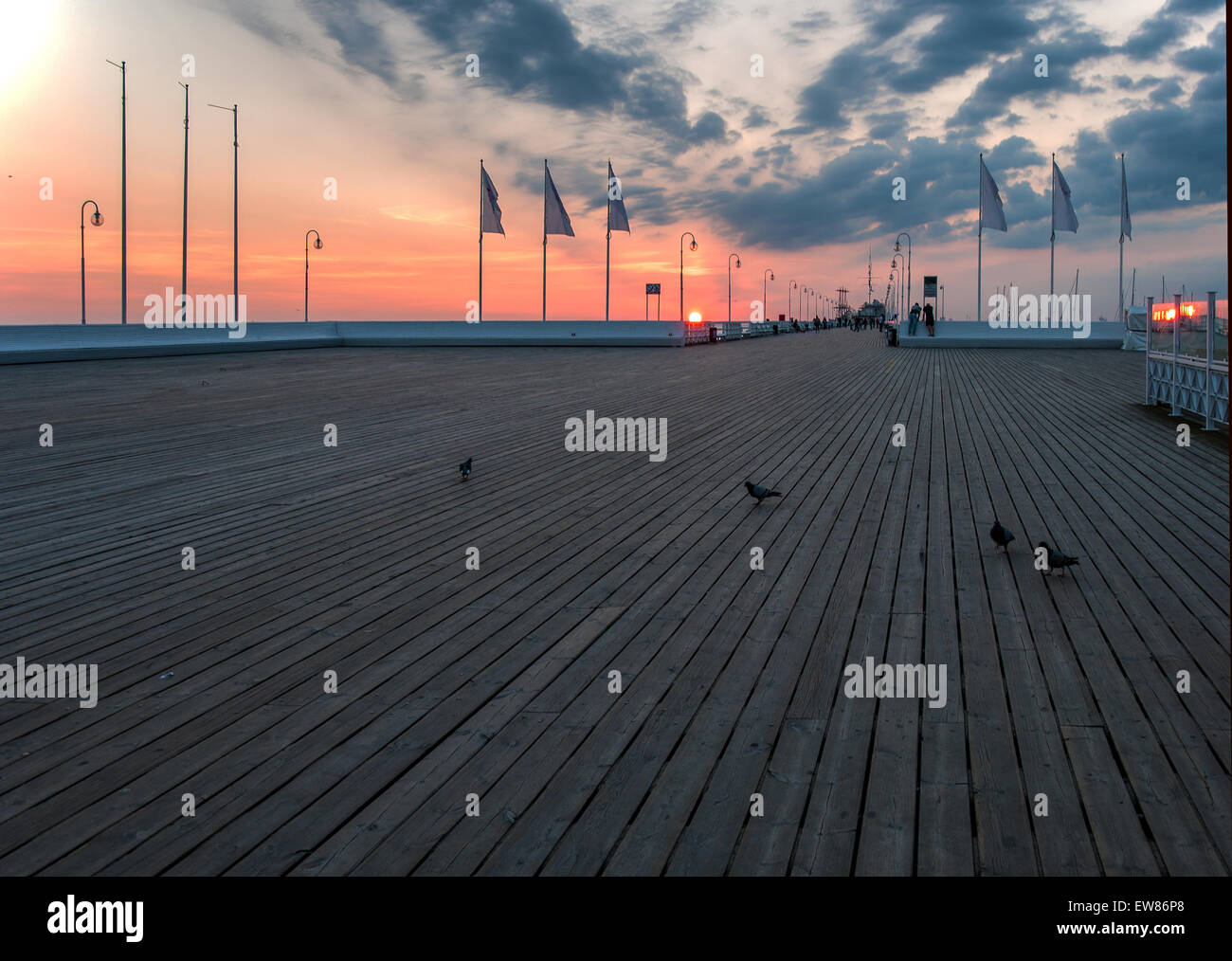 Sonnenaufgang auf dem Holzsteg (Molo) in Sopot, Polen, mit Menschen und Tauben Stockfoto