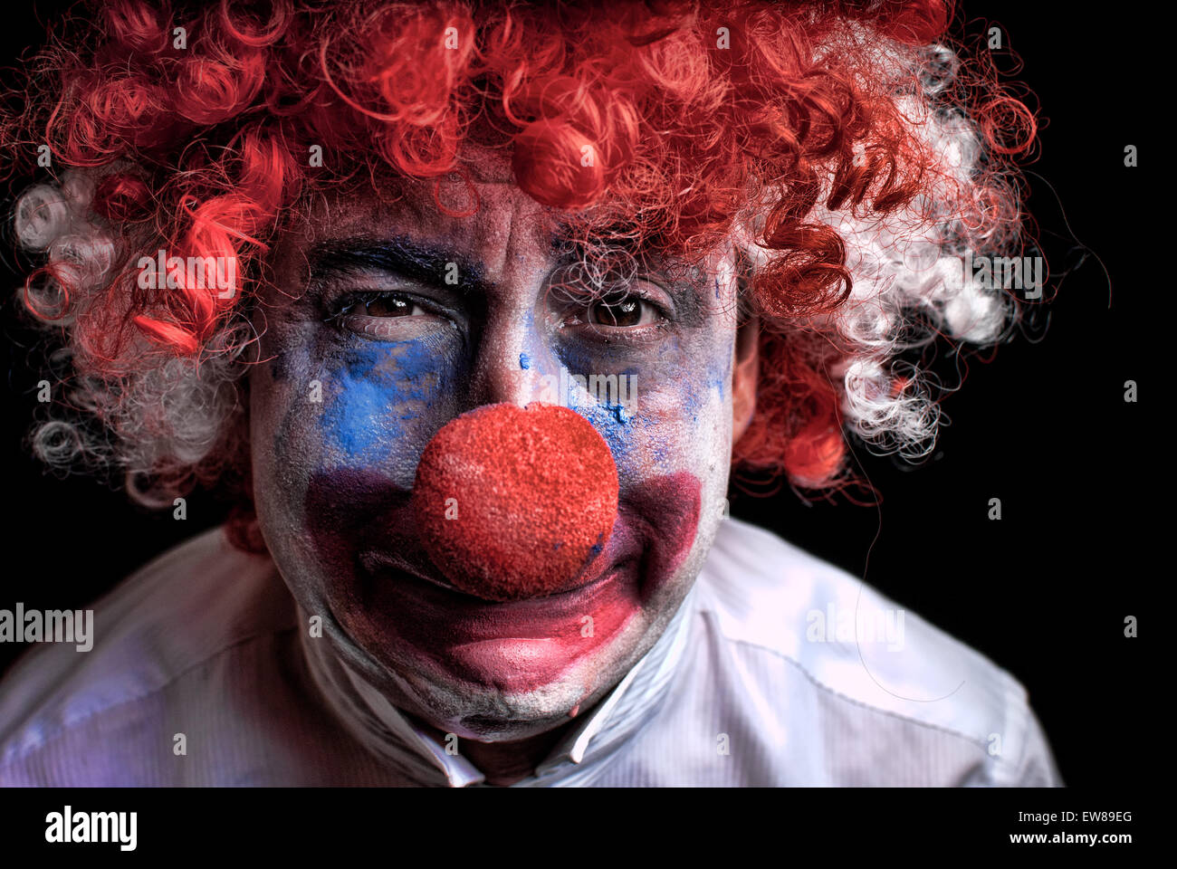 Nahaufnahme eines traurig, aufgeregt, weinende Clown mit einer roten Nase auf schwarzem Hintergrund Stockfoto