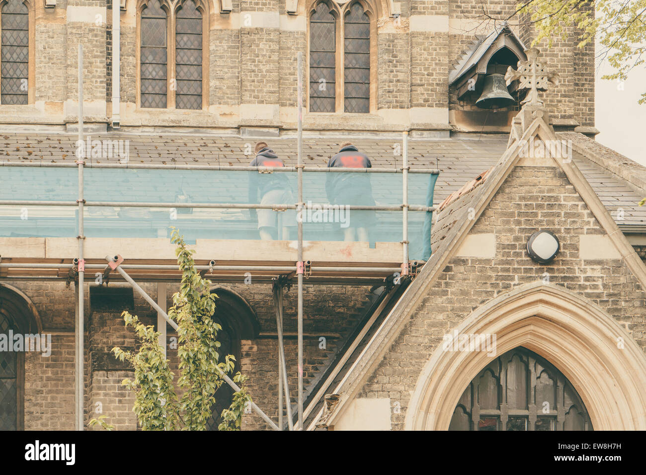 Bauherren, Reparatur Dach einer Kirche steht auf einem Gerüst, Kirche im Hintergrund Stockfoto