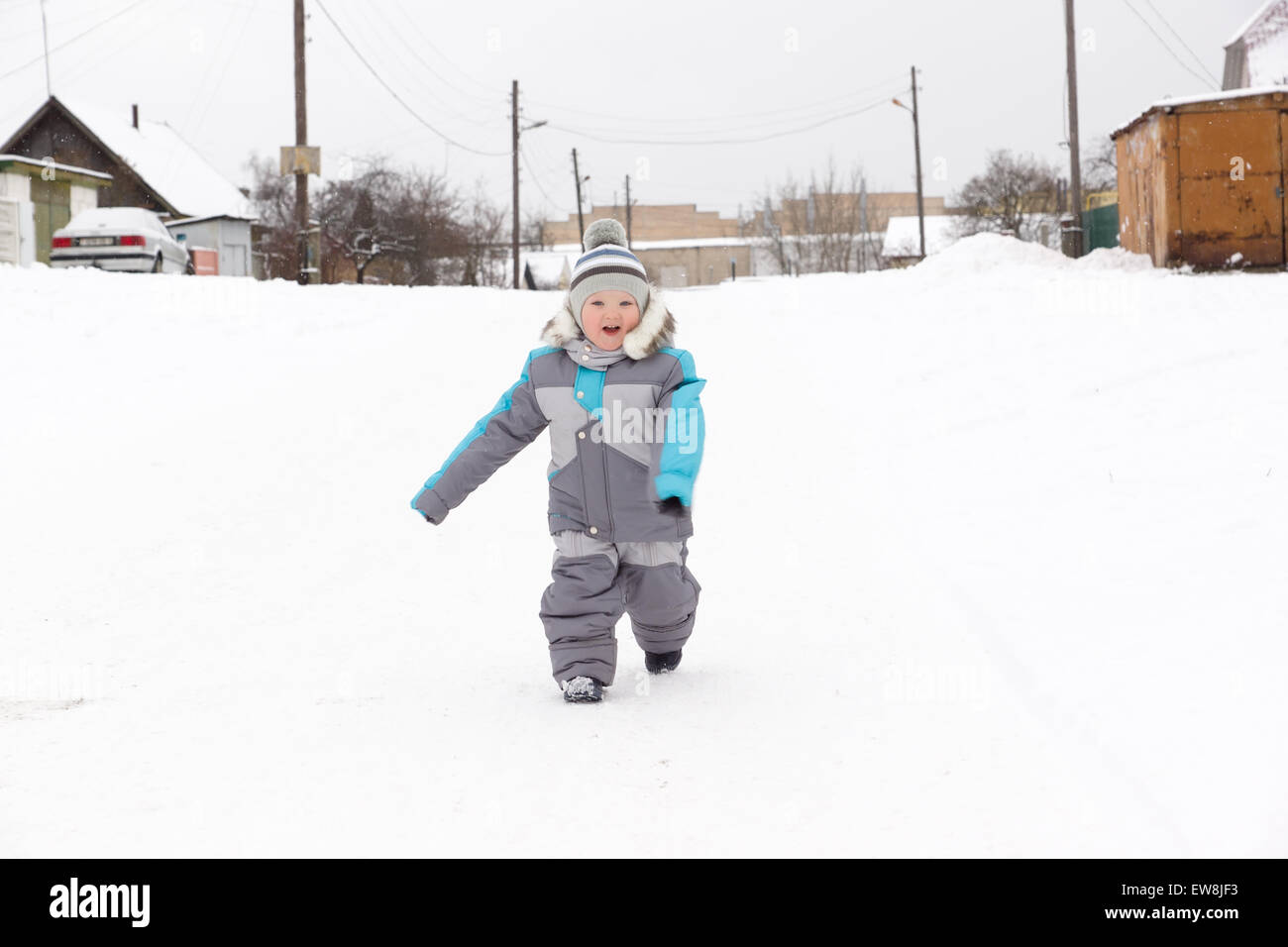 kleiner Junge in einem Overall laufen durch den Schnee Stockfoto