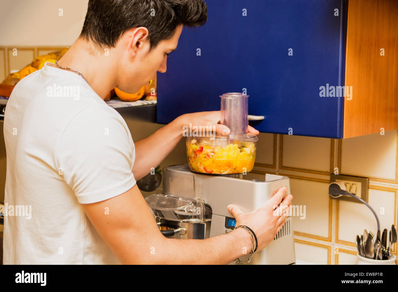 Junger Mann bereitet gesunde Smoothie Drink Mixer, hergestellt aus gemischten frischen tropischen Früchten bietet einen Toast oder Gruß Stockfoto