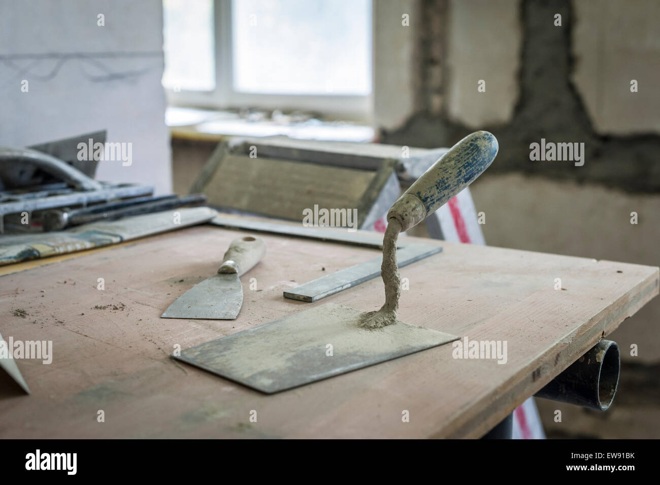 Werkzeuge eines Gipser/Mason während seiner Pause auf einem Tisch auf einer Baustelle Stockfoto