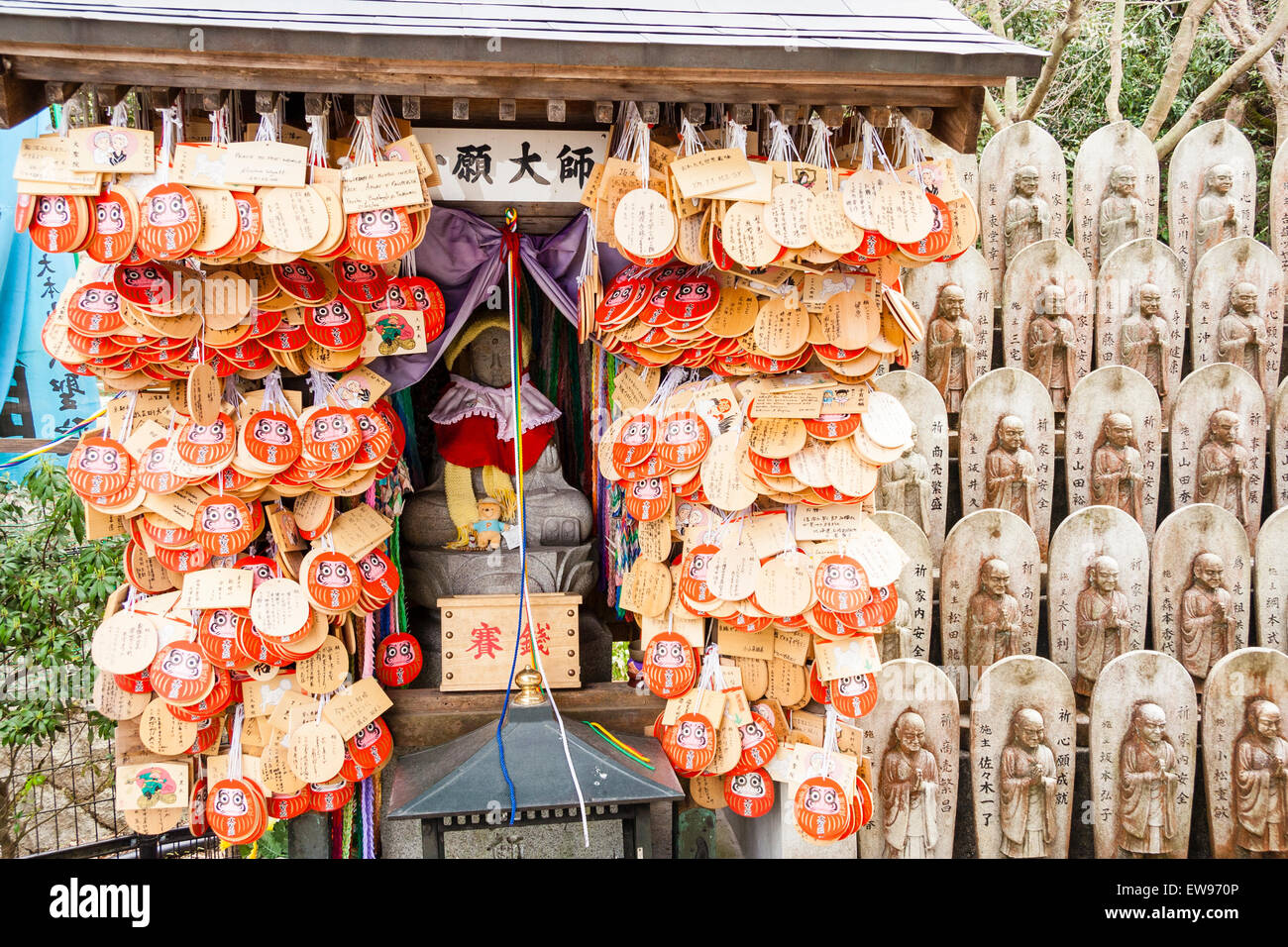 Daisho-in-Tempel auf Miyajima Island. Große sitzende Jizo-Statue, Ichigan Daishi, in einem kleinen Holzschrein, der von vielen Daruma umgeben war, stand auf ema-Tafeln Stockfoto