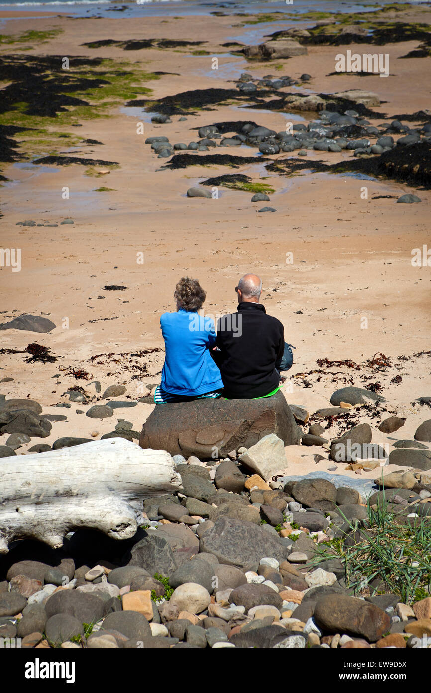 Älteres paar sitzen auf Embleton Strand Northumberland Blick auf das Meer Stockfoto