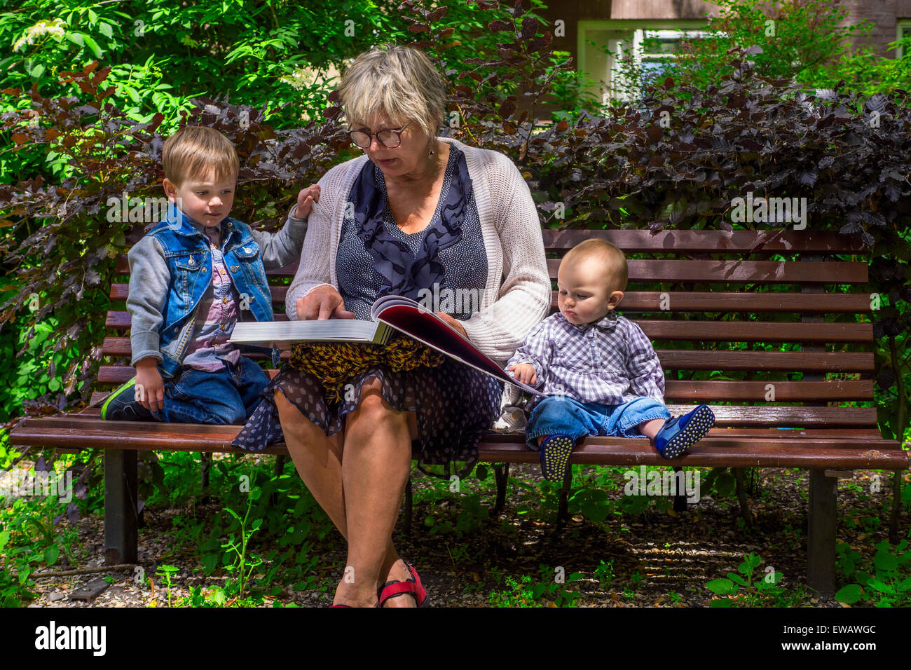 Großmutter zu ihren Enkeln im Park lesen Stockfoto