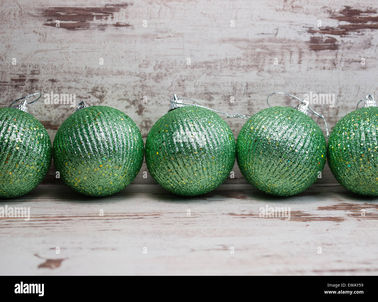 Grüne Weihnachtskugeln in einer Reihe über hölzerne Hintergrund Stockfoto