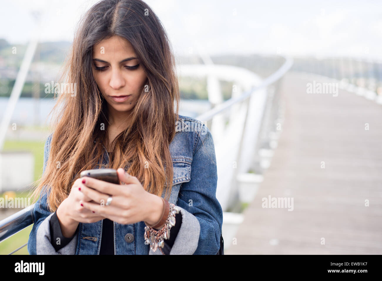 Junge Brünette Frau, die ihr Smartphone im freien Stockfoto