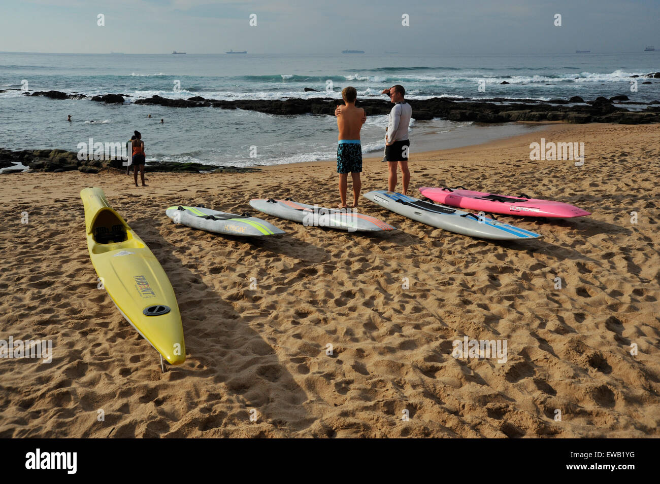 Zwei Männer stehen auf Strand und Blick auf das Meer neben Surf Ski- und Paddelboote, am frühen Morgen, Umhlanga Rocks, Durban Stockfoto