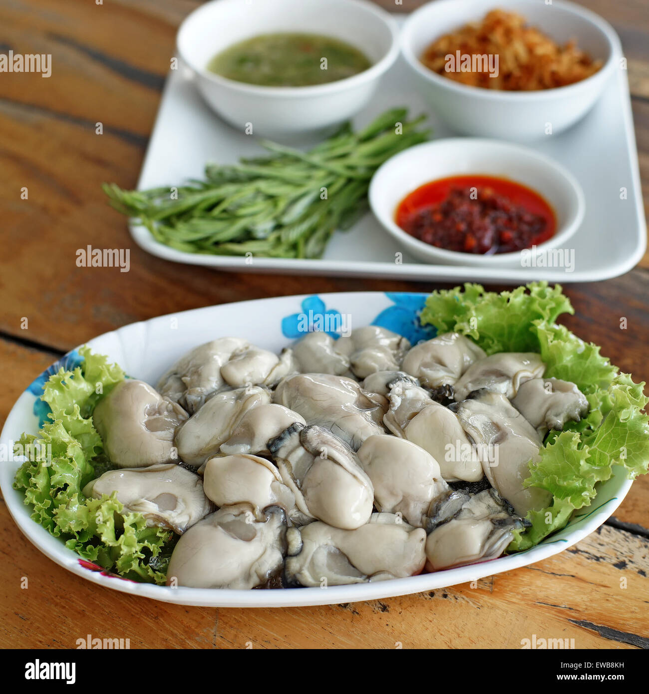 frische Austern mit Beilagen auf Schreibtisch aus Holz Stockfoto