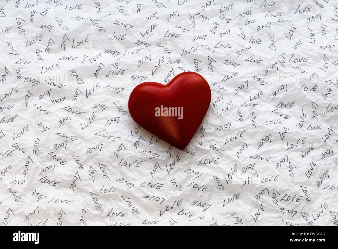 Rotes Herz auf weißes Seidenpapier eingeschrieben mit dem Wort Liebe Stockfoto