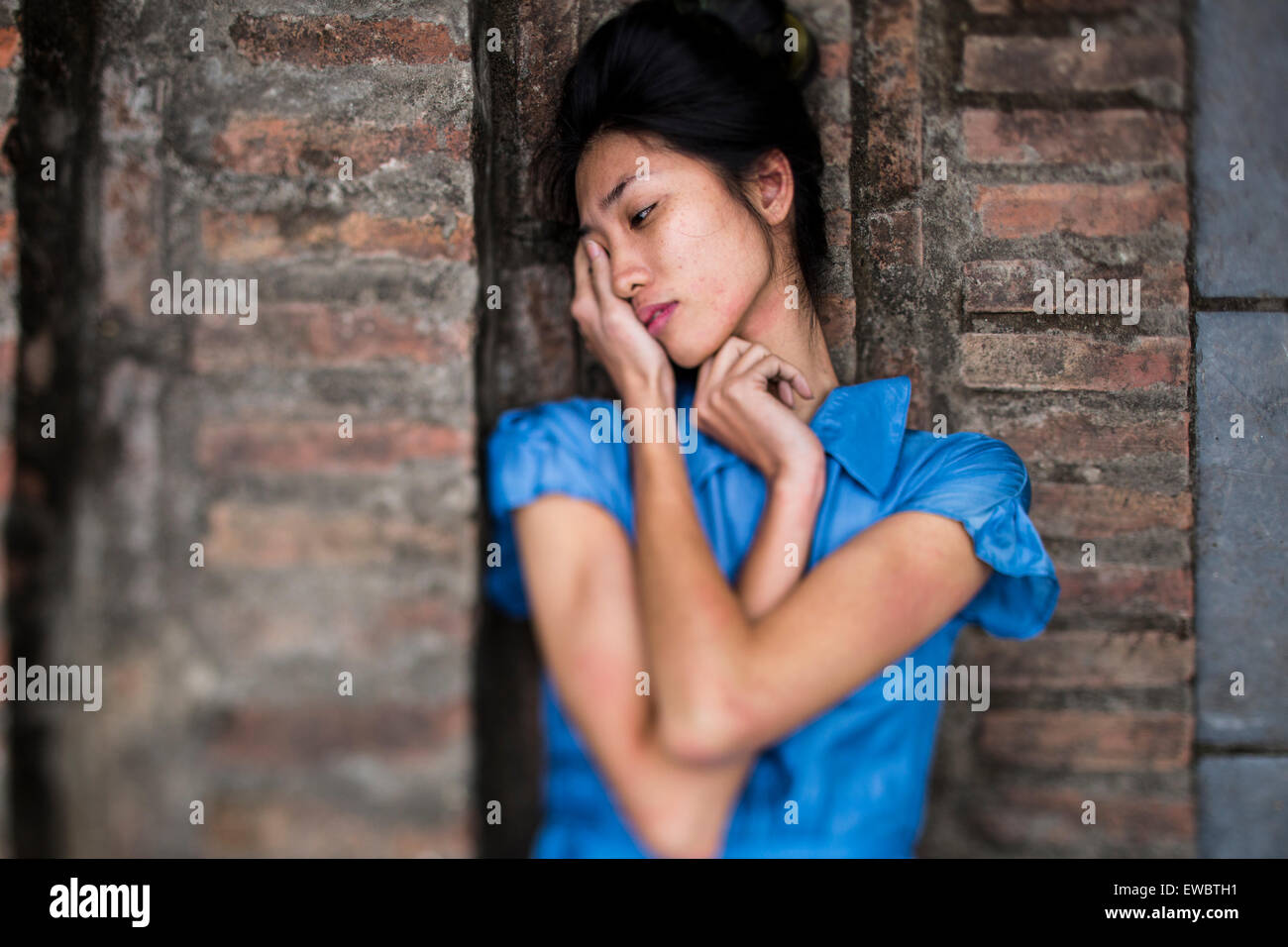 Eine junge vietnamesische Frau in einem blauen Kleid, liegend auf Steintreppen im ländlichen Hanoi, Vietnam. Stockfoto