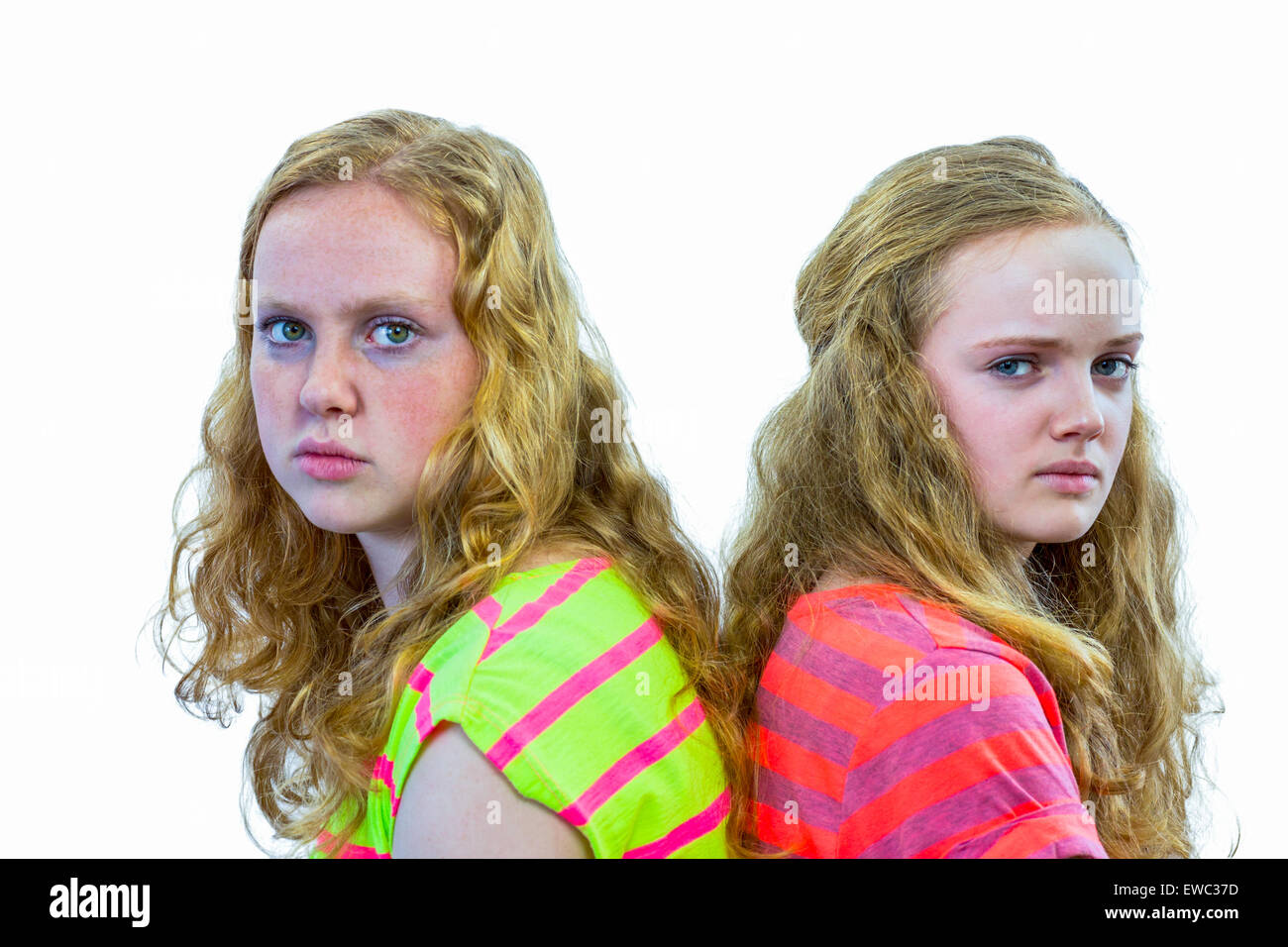 Zwei böse europäische Teenager Schwestern mit Rücken berühren isoliert auf weißem Hintergrund Stockfoto