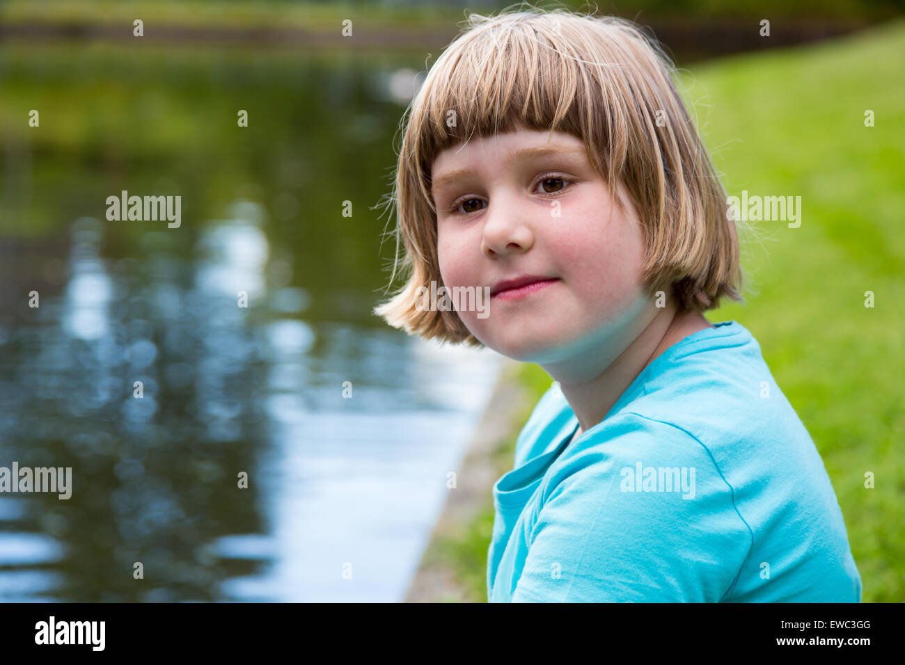 Junge blonde Holländerin sitzen am Wasser Teich im park Stockfoto