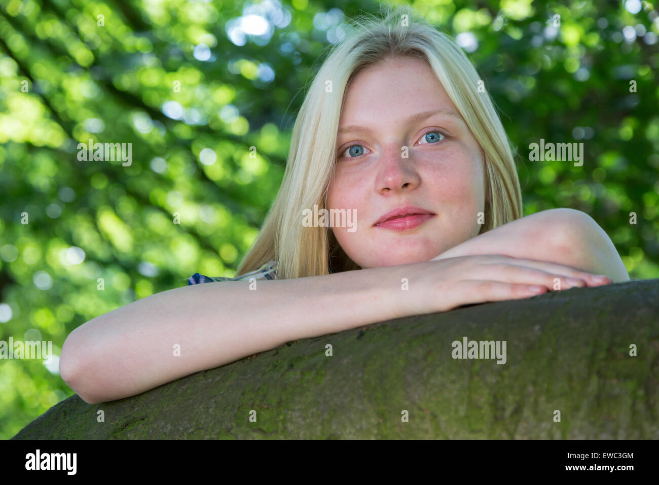 Blonde kaukasische Teenager stützte sich auf Zweig des Baumes in der Natur Stockfoto