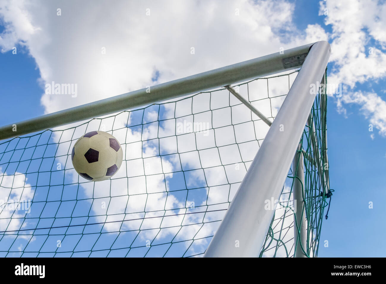 Fußball in der Ecke des Tores mit blauem Himmel und weißen Wolken geschossen Stockfoto