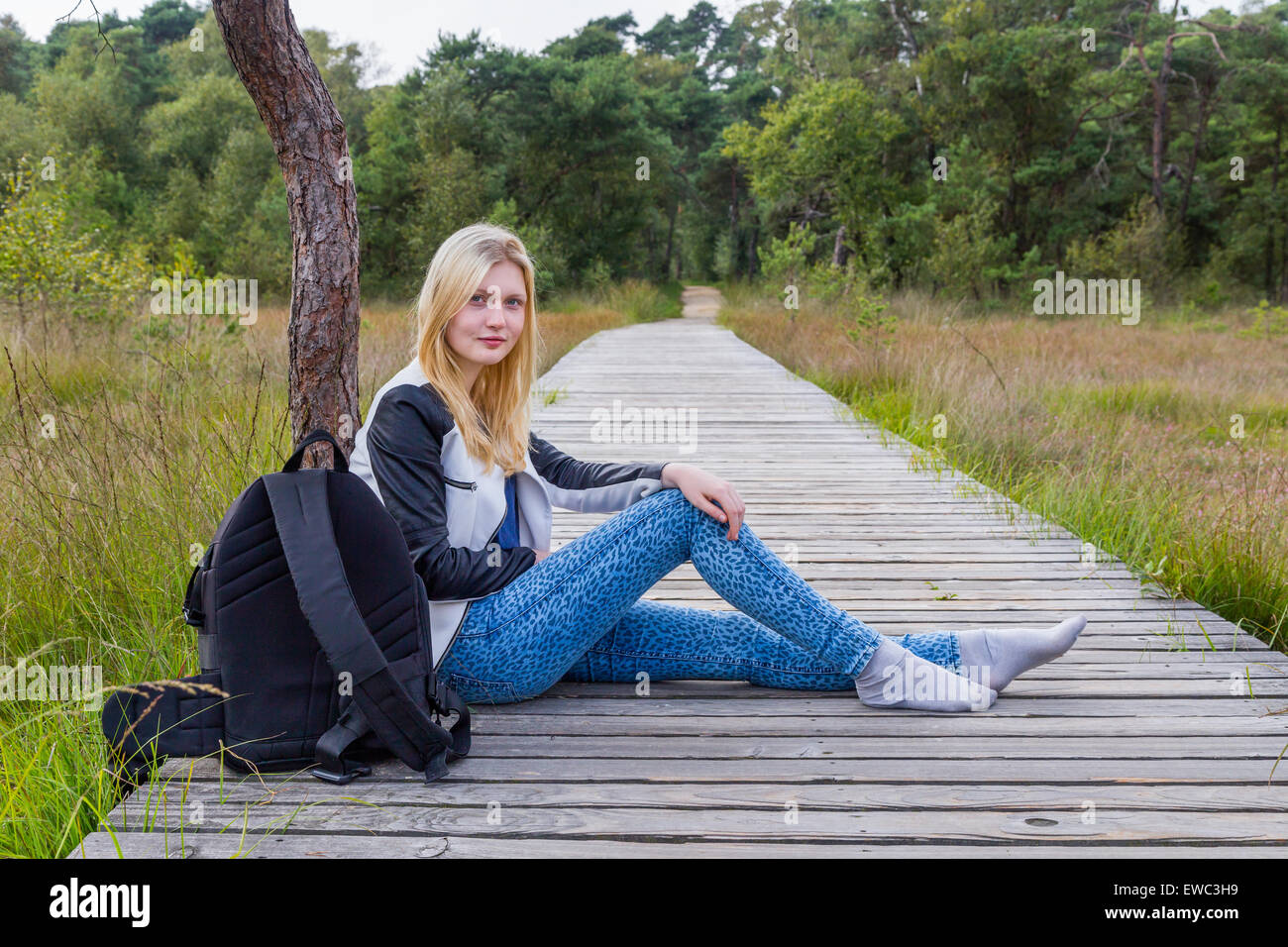 Blonde kaukasische Teenager ruht auf hölzernen Wanderweg im Wald Stockfoto