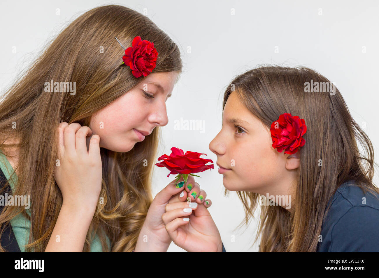 Porträt von zwei kaukasische Mädchen im Teenageralter riechen rote Rosen Stockfoto