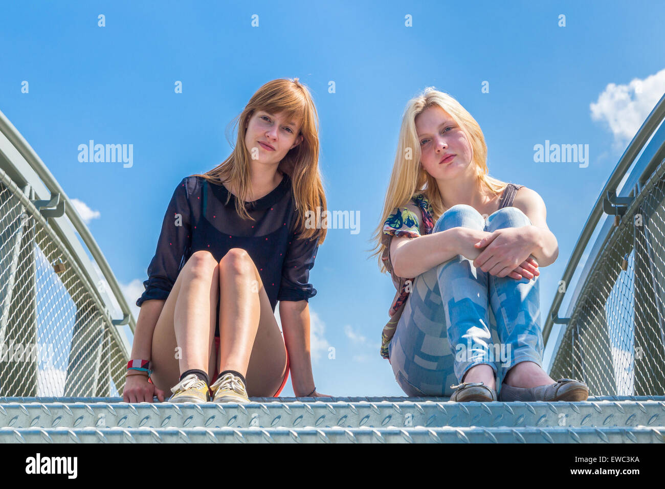 Zwei niederländische Teenager Freundinnen sitzen auf Metallbrücke mit blauem Himmel Stockfoto