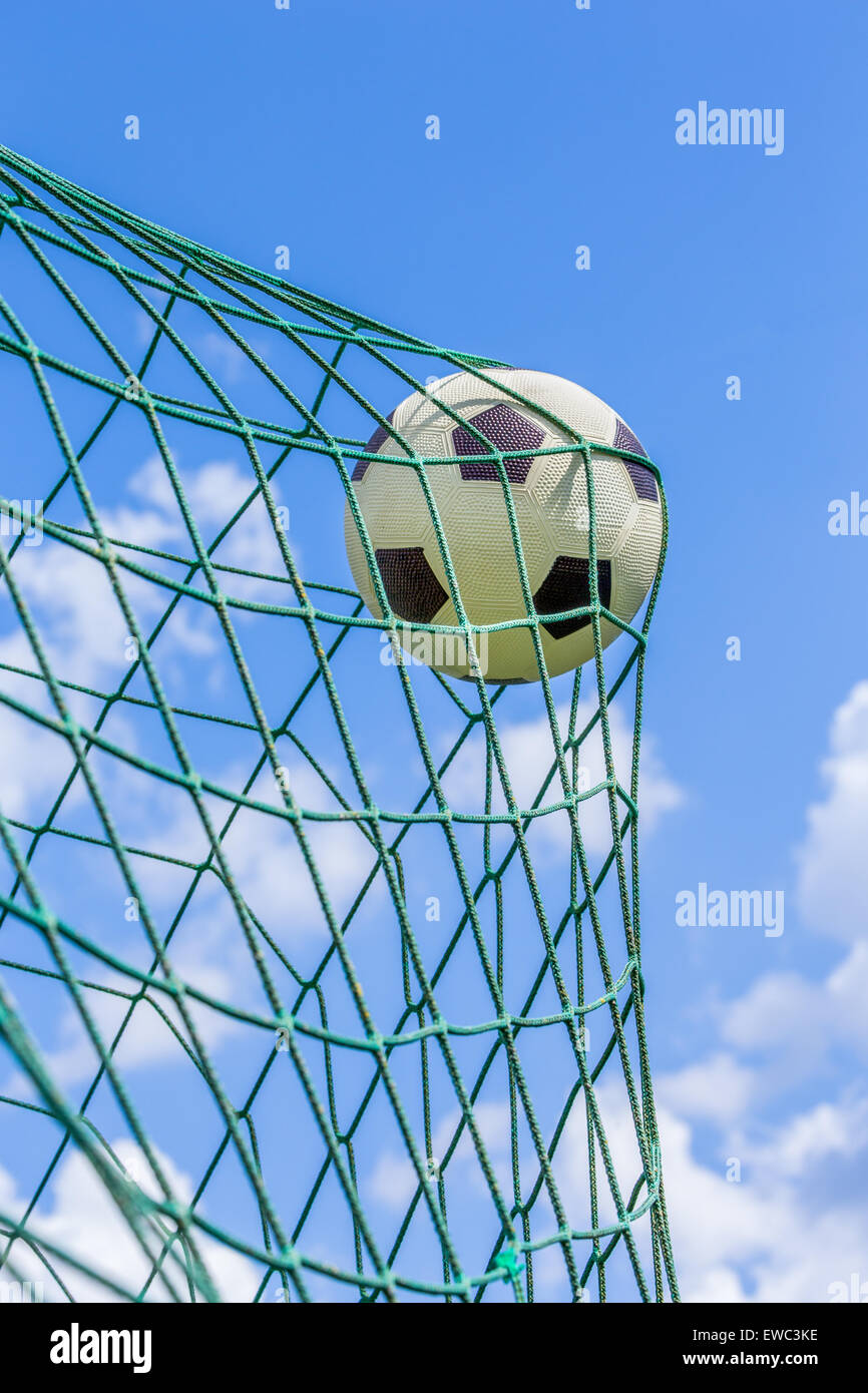Schwarz / weiß Fußball im Tor-Netz mit blauem Himmel und weißen Wolken gefangen Stockfoto