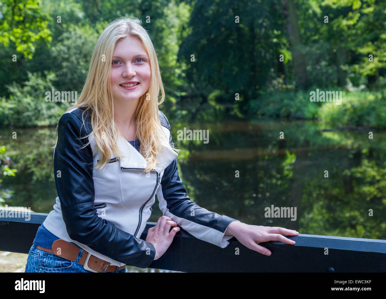 Kaukasische Teenager Blondine stützte sich auf Zaun in der Nähe von Wasser Teich im Wald Stockfoto