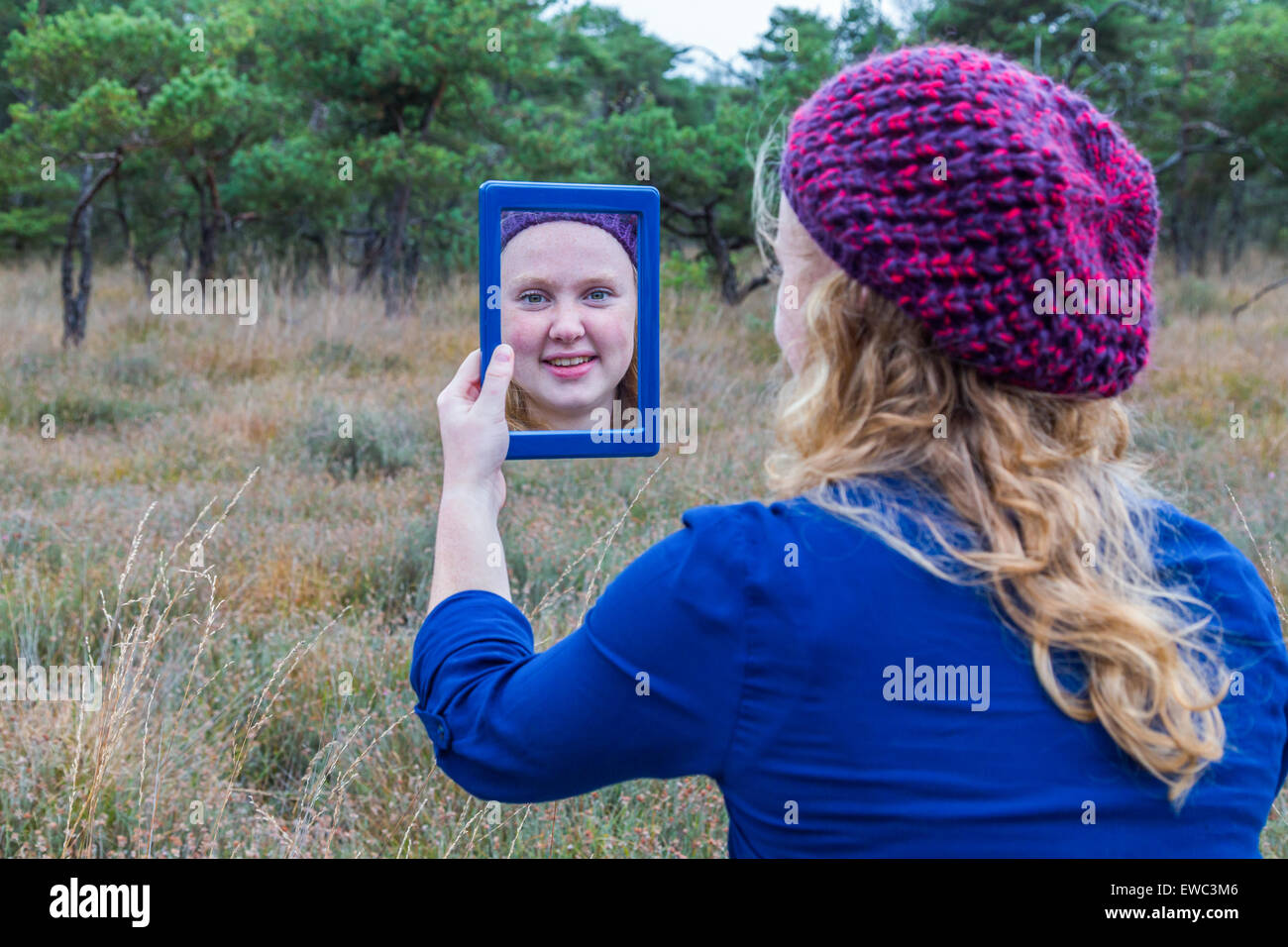 Niederländische Teenager-Mädchen halten Spiegel in der Natur und sich selbst zu betrachten Stockfoto