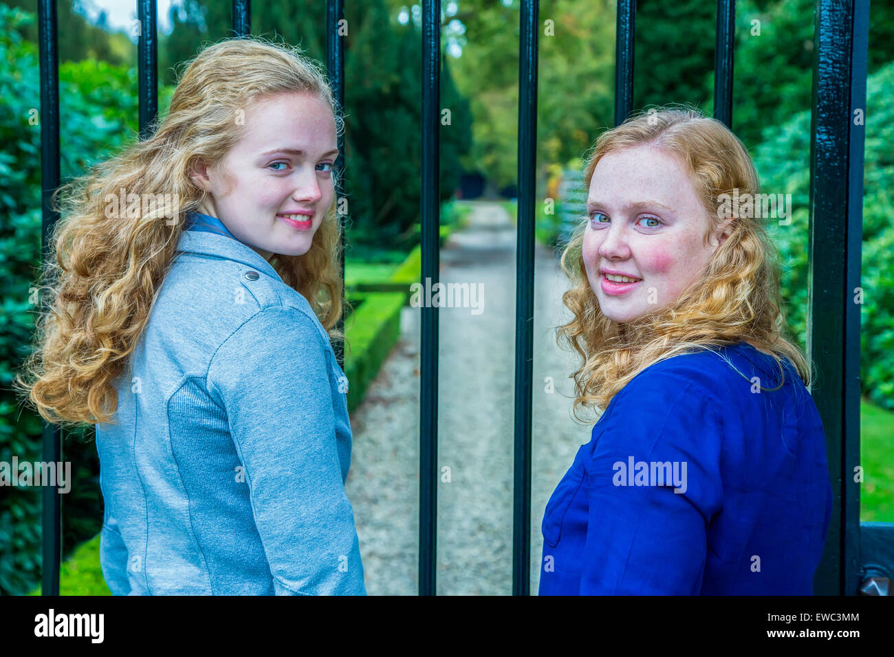 Zwei kaukasischen Teenager Schwestern am Zaun des Gartens im Rückblick Stockfoto