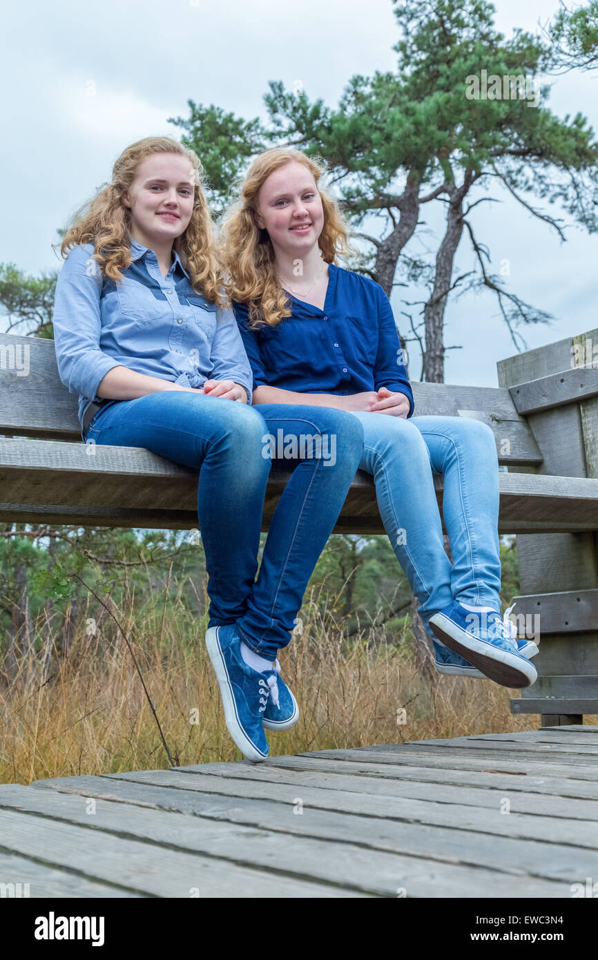 Zwei niederländische Mädchen sitzt auf einer Holzbank in der Natur Stockfoto