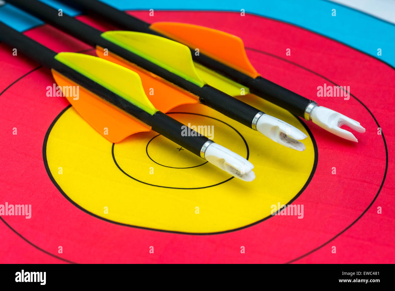 Drei Pfeile sitzen auf Bullseye eines Papier-Ziels Stockfoto