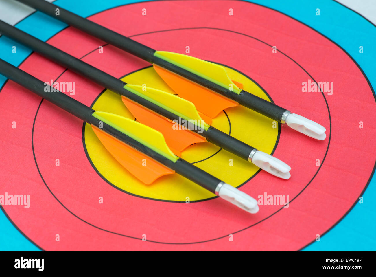 Drei Pfeile sitzen auf Bullseye eines Papier-Ziels Stockfoto