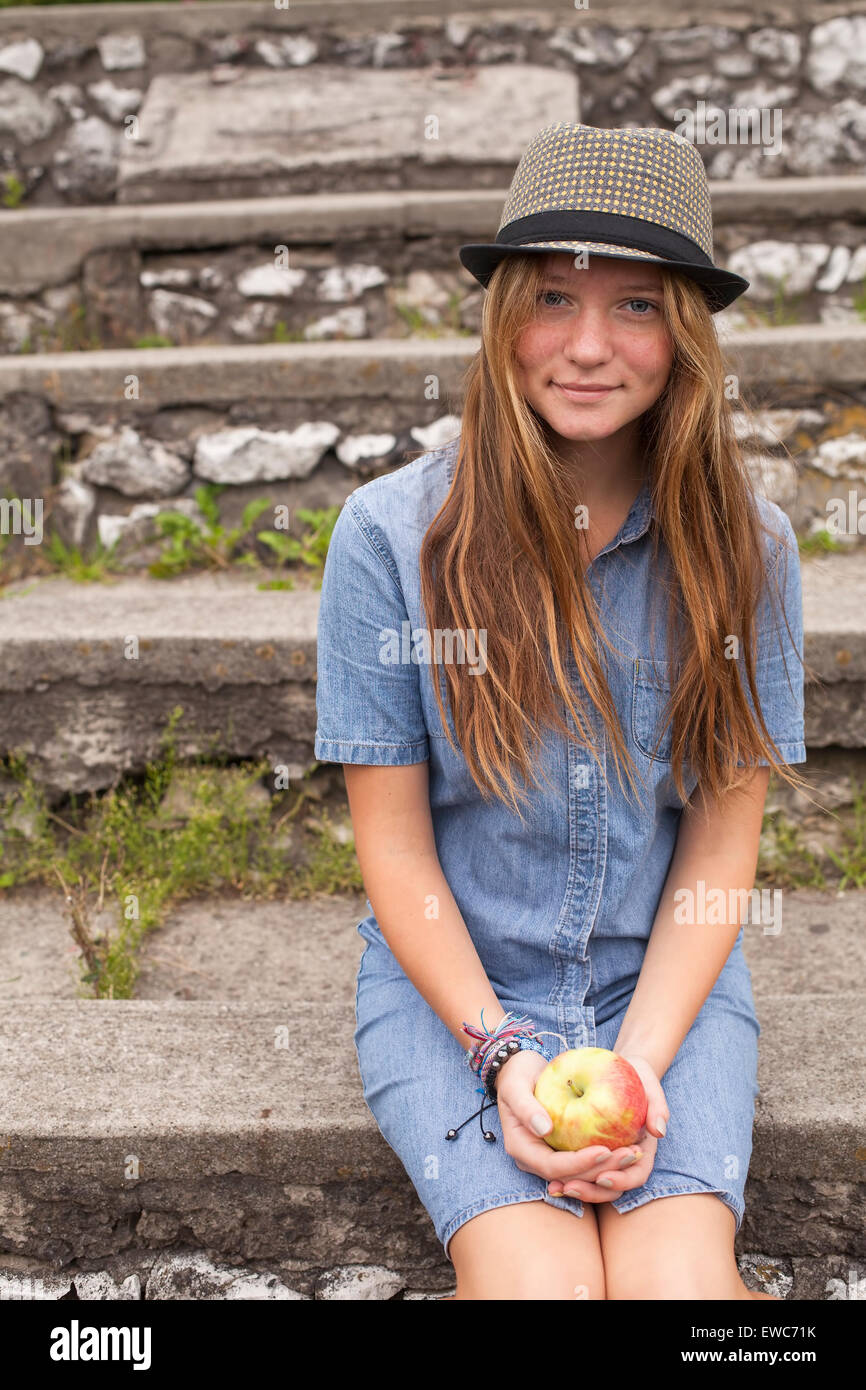 Teenager-Mädchen Hipster in einen Hut und einen Apfel in der Hand, im Freien. Stockfoto