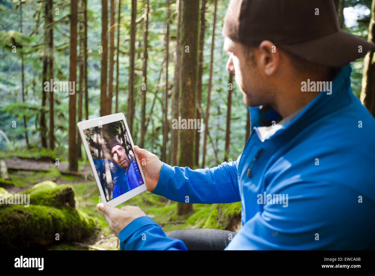 Ein Mann nutzt eine Tablette, ein Selbstporträt in den Wald zu nehmen Stockfoto