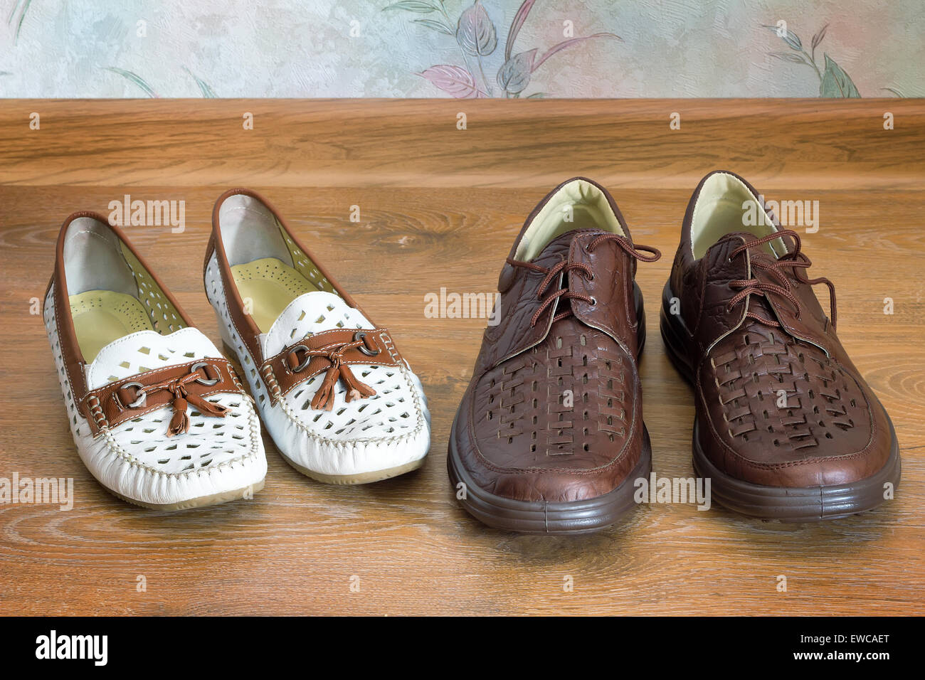 Auf dem Boden im Haus sind in der Nähe von weißen Damen Mokassins und Mens dunkle Lederschuhe. Stockfoto