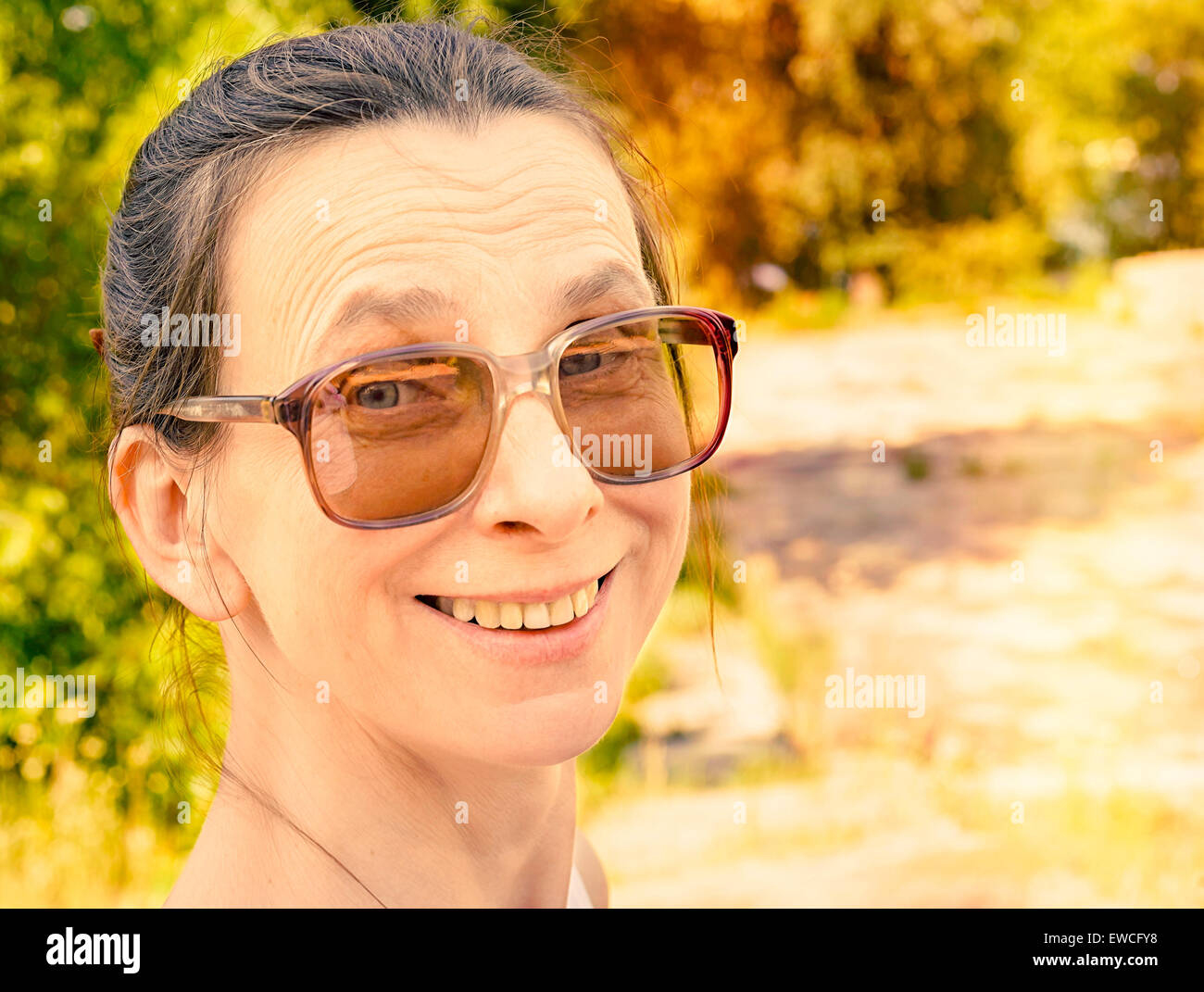 Snapshot einer lächelnden kaukasischen erwachsenen Frau mit großen Vintage Sonnenbrille Stockfoto