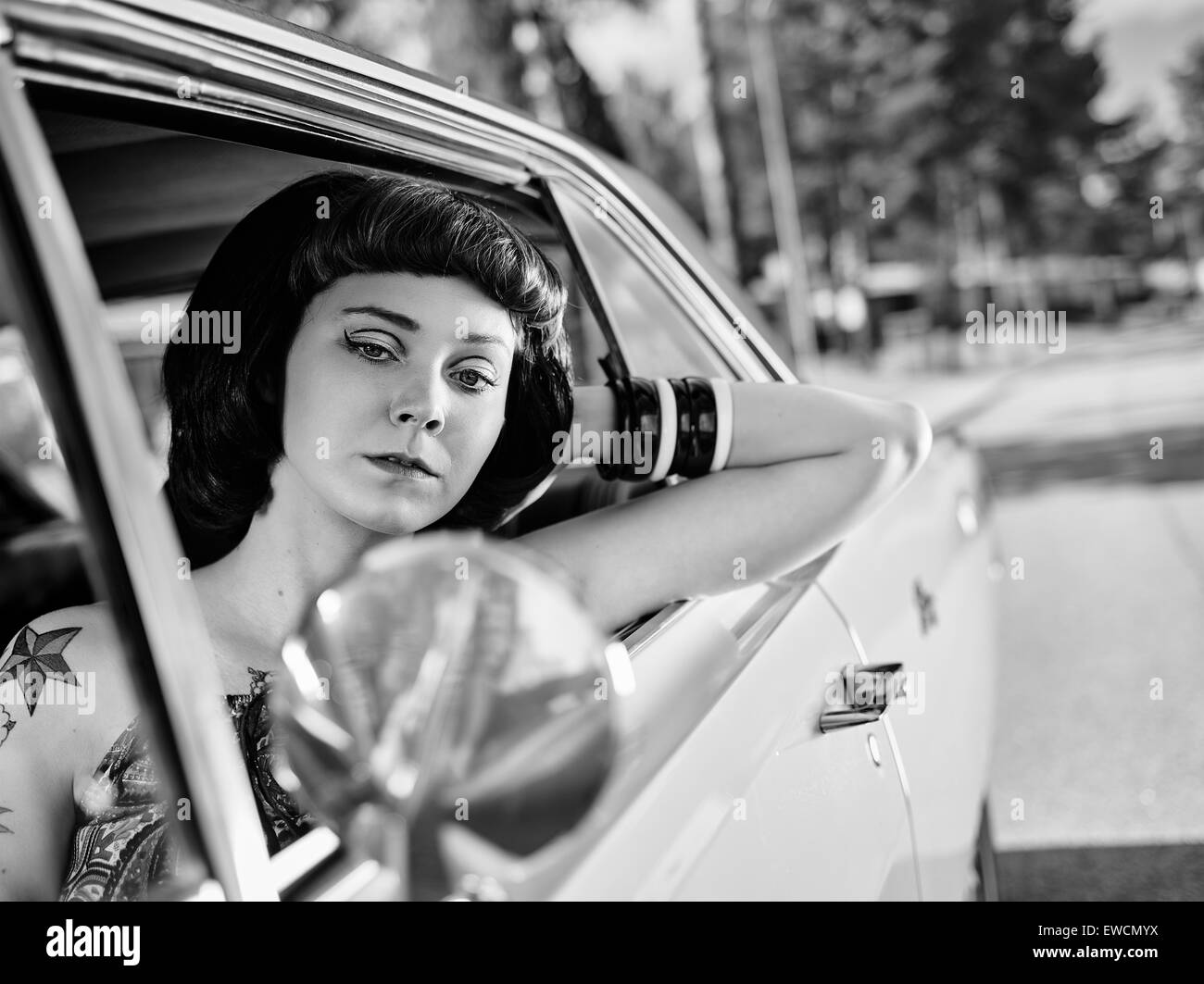 Schönes Mädchen sitzt im Inneren der alten Dodge, 70er Jahre Stil gestaltet, schwarz / weiß Bild. Stockfoto