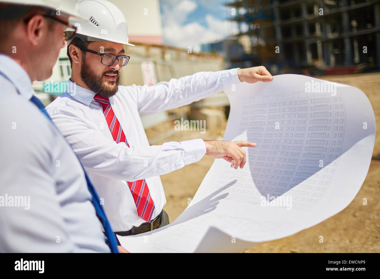 Männliche Architekten in Helme diskutieren Blaupause außerhalb Stockfoto