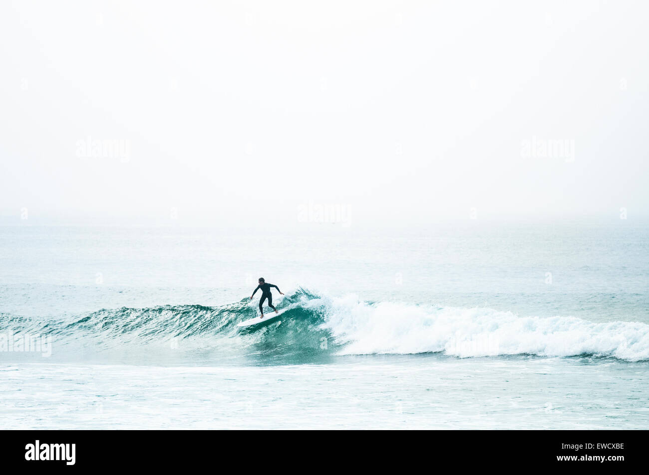 Surfer nach unten schieben einer Glasigen grüne Welle in Cornwall. Stockfoto