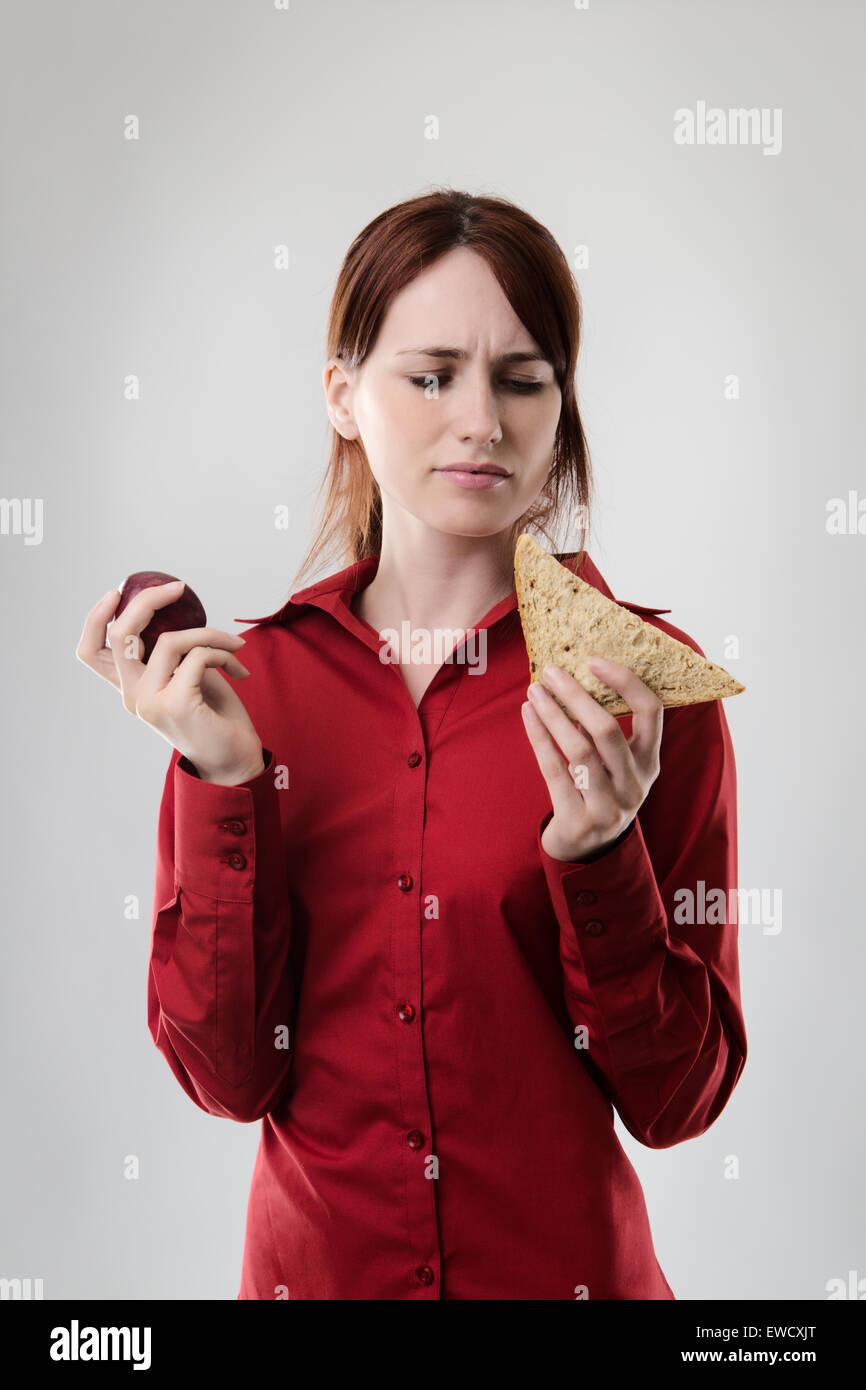 Geschäftsfrau hält ein Sandwich und ein Apfel nicht sicher, was zu essen Stockfoto