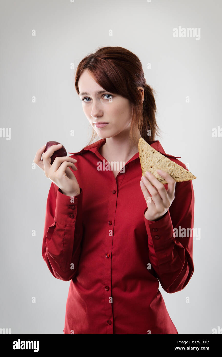 Geschäftsfrau hält ein Sandwich und ein Apfel nicht sicher, was zu essen Stockfoto
