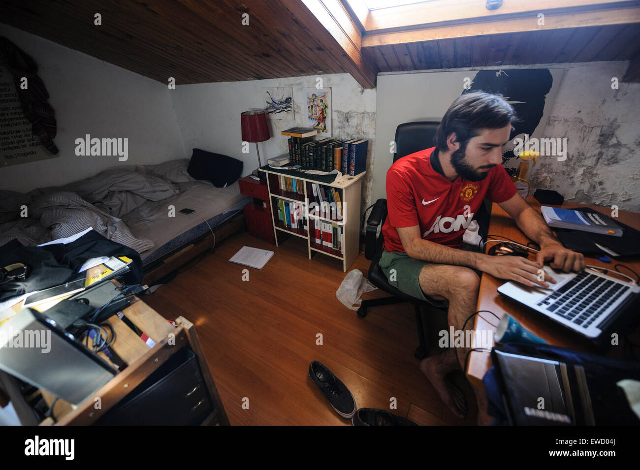 Junger Mann arbeitet an seinem Laptop in seinem Schlafzimmer Stockfoto