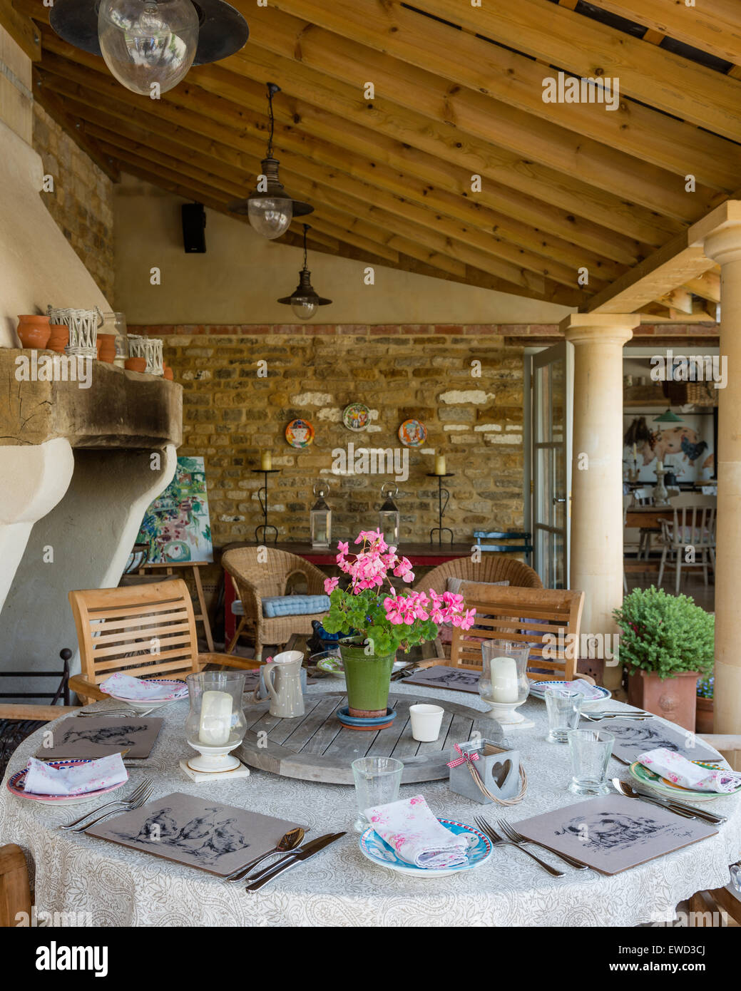 Runder Tisch und Holzstühlen im Garten Zimmer / Loggia mit Sandstein Säulen und geneigten Deckenbalken Stockfoto
