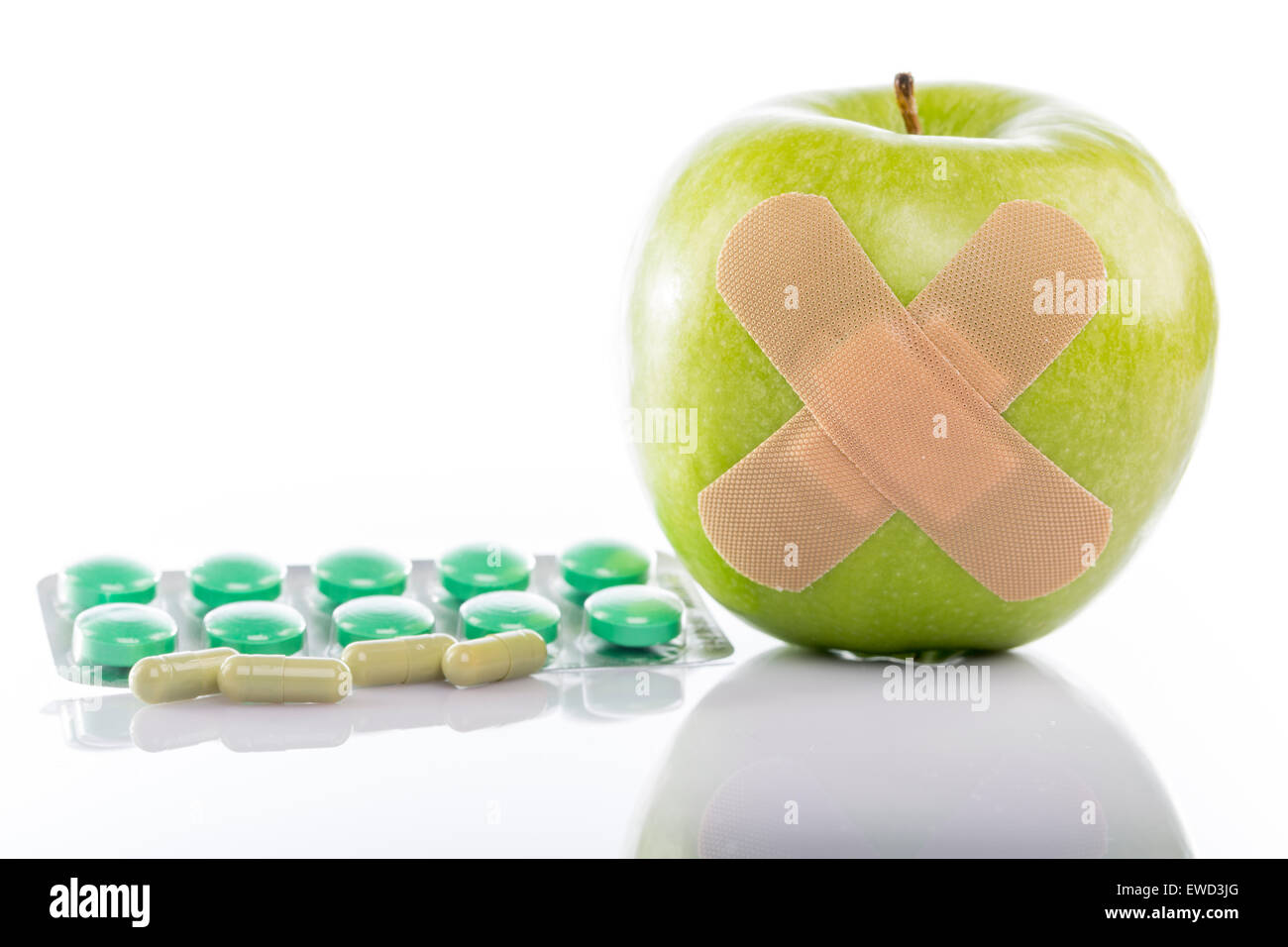 Grüner Apfel mit einem Pflaster und Varios Pillen auf weißem Hintergrund Stockfoto