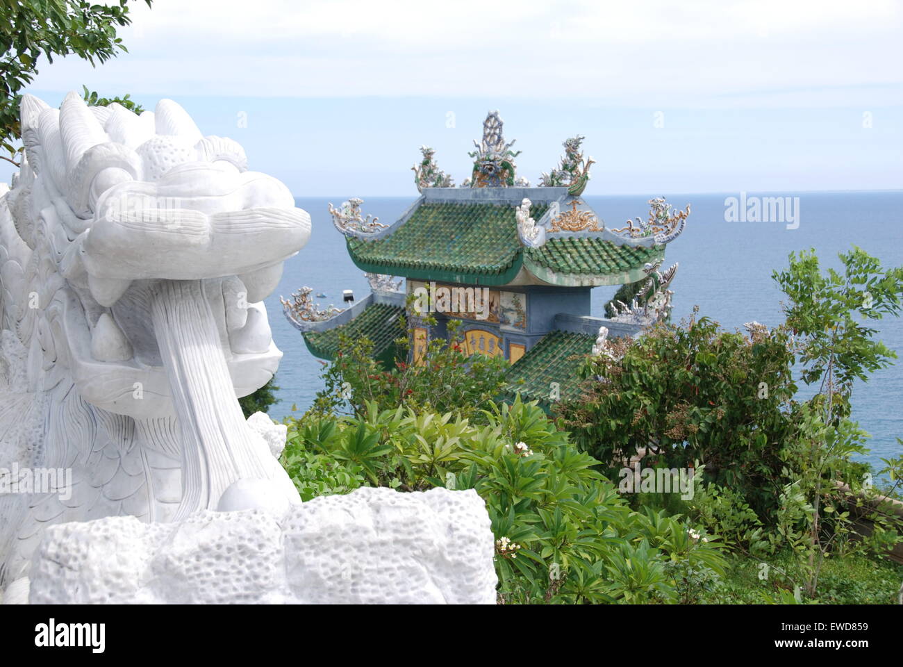 Drachen-Statue Meer Blauwasser Tempel Kloster Bäume Berg hoch Liebe beten Himmel Wolken China Vietnam Asien weiß traditionelle Stockfoto