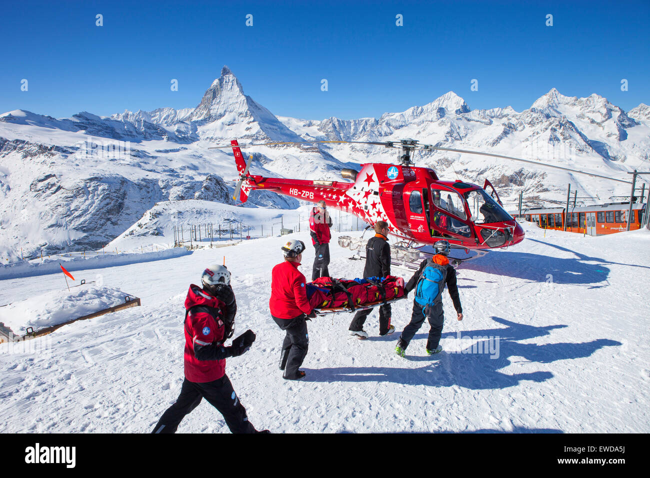 Rettungskräfte tragen ein verletzte Skifahrer zu einem Helikopter der Air Zermatt im Skigebiet Gornergrat in Zermatt Stockfoto