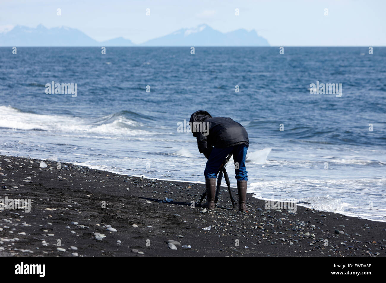 Fotografen, die Fotos von Eisbergen Abwasch am schwarzen Sandstrand am Jökulsárlón Island Stockfoto