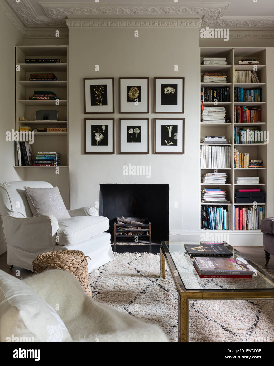 Paar Sessel im Wohnzimmer mit Couchtisch aus Glas gekrönt, Alkoven-Buch-Regal und Kamin Stockfoto