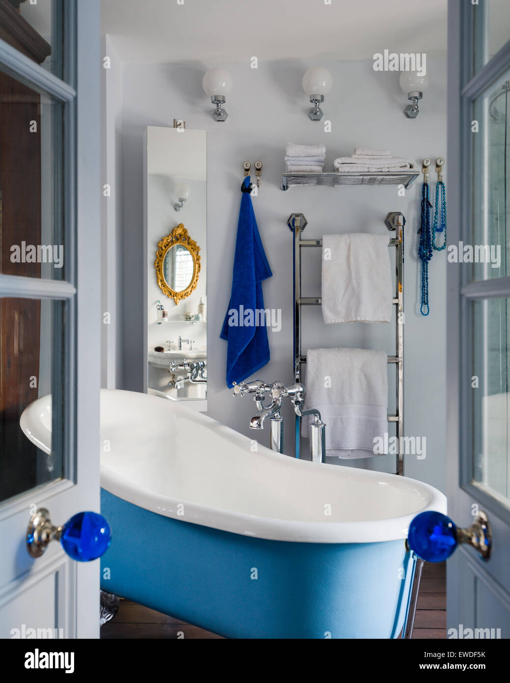 Blick durch geöffnete Flügeltüren zur Badezimmer mit blauen freistehende Roll Top Badewanne Stockfoto