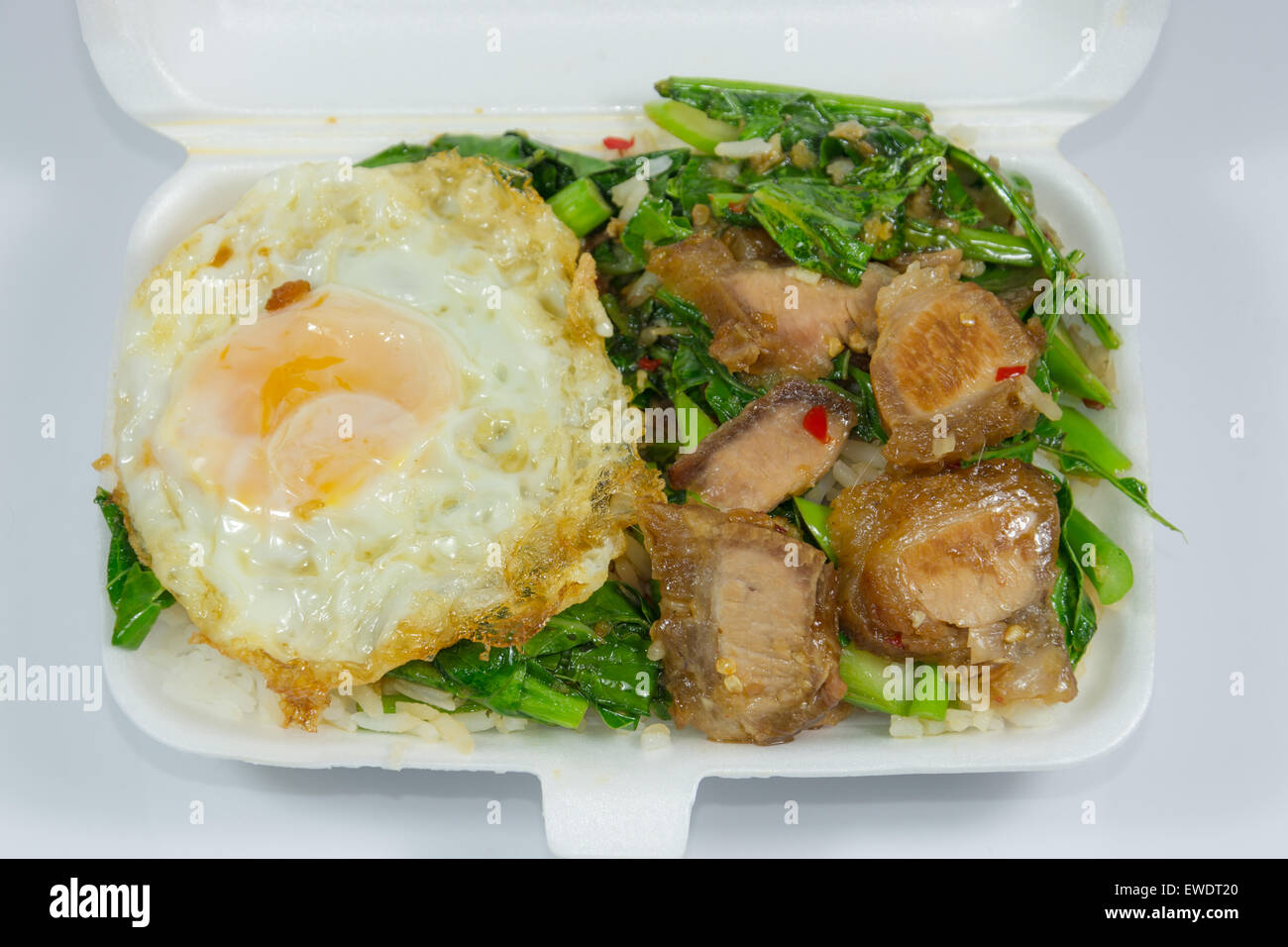 Thai Lunchpaket Menü, Schweinebauch gebraten mit Grünkohl und mit Spiegelei obenauf. Stockfoto